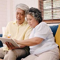 elderly asian couple sitting and looking at the tablet